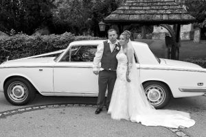 bride and groom by a car